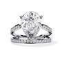 ring features a commanding Pear solitaire framed by two distinct architectural bands one linear and one curved both encrusted with Pavé diamonds