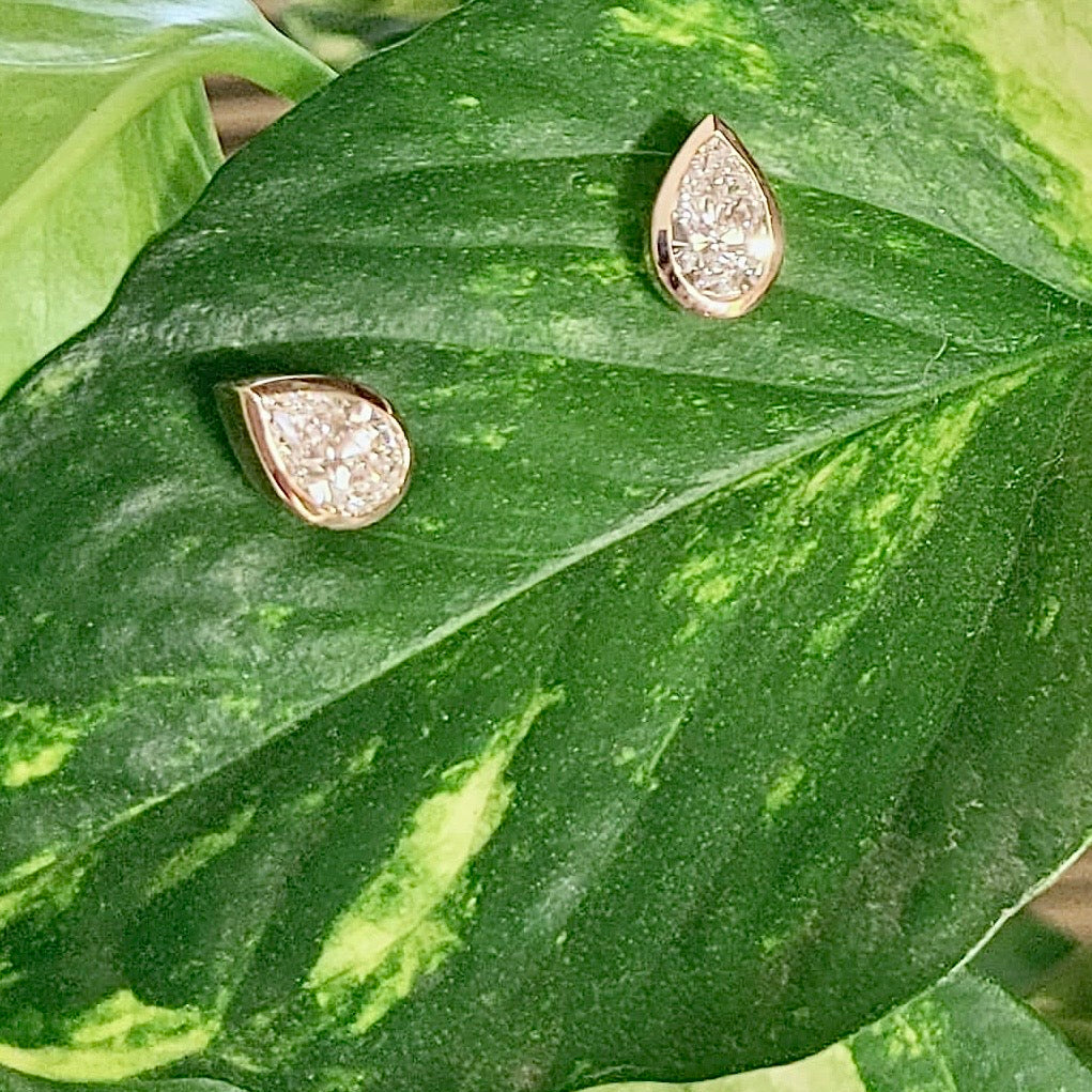 Pair of pear diamond earrings on a green leaf