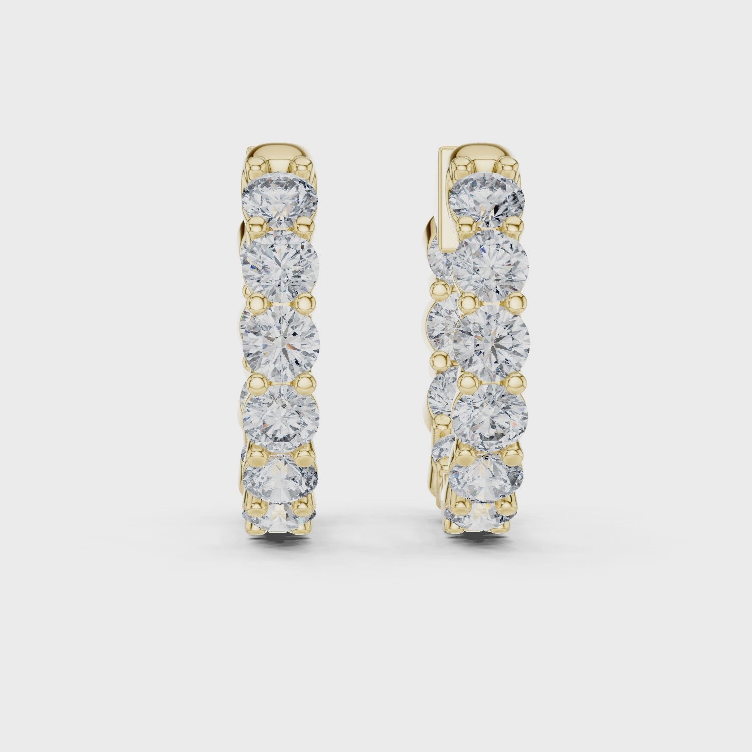 Gold hoop earrings with diamonds on a white background