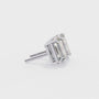Pair of emerald-cut diamonds with gold prongs on a white background