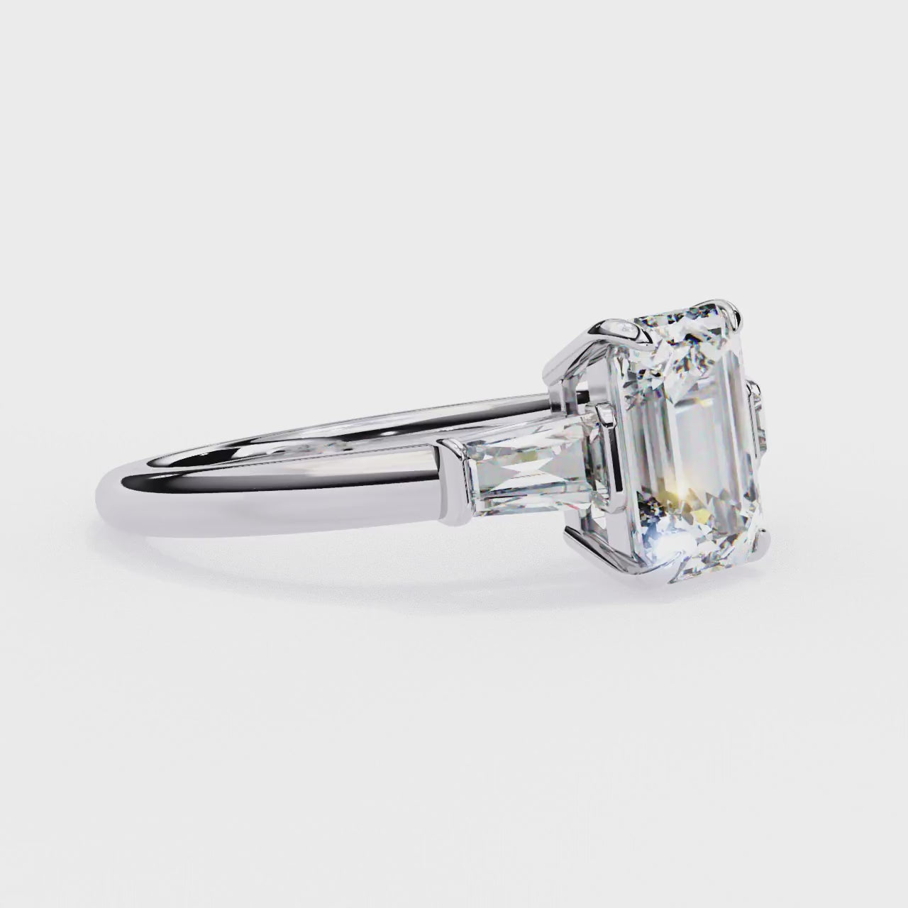 ring features a magnificent Emerald-cut centre flanked by two tapering baguette diamonds
