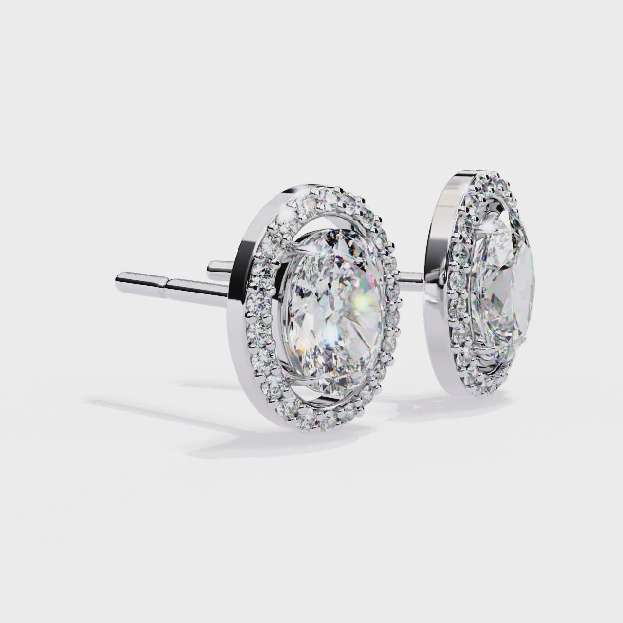 Pair of gold earrings with oval diamonds on a white background