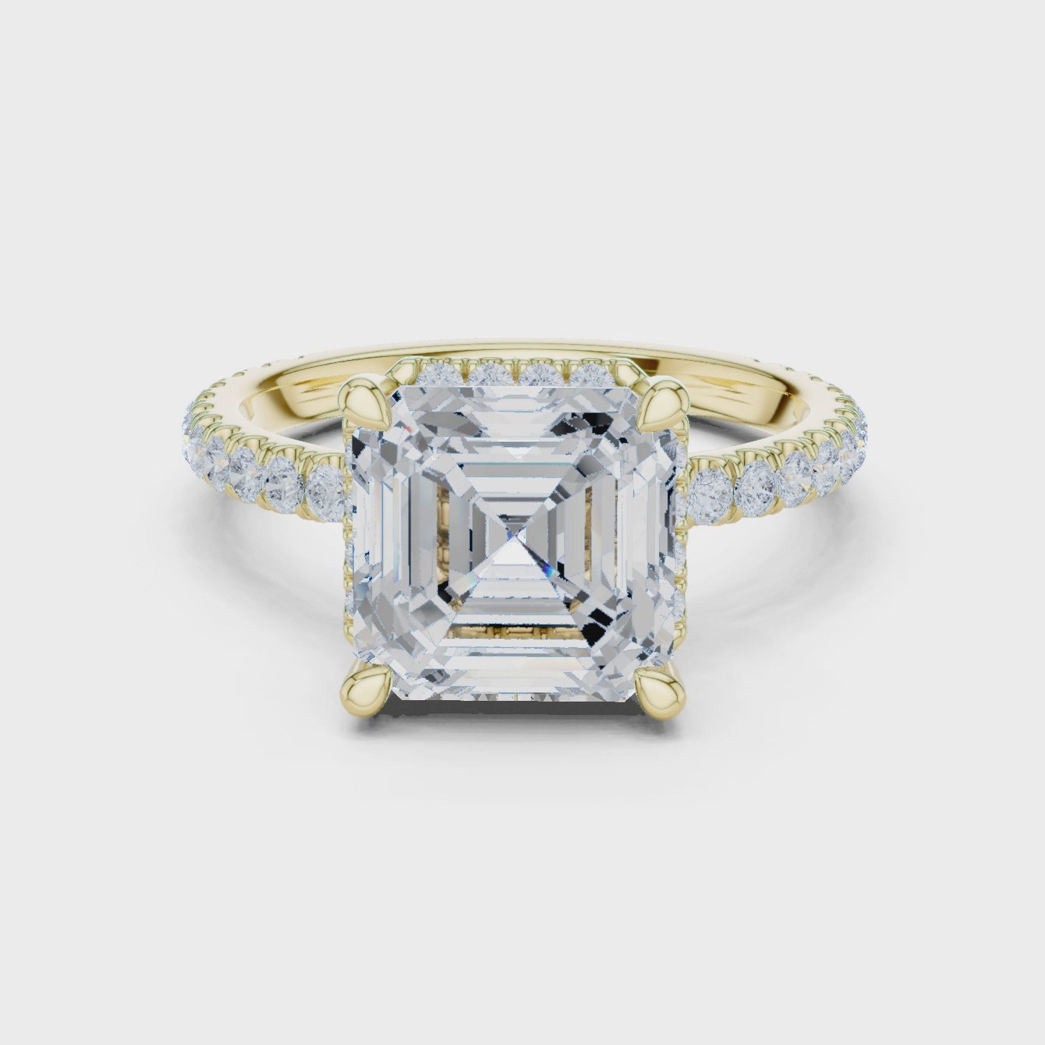 Gold ring with a large asscher diamond and smaller diamonds on the band against a white background
