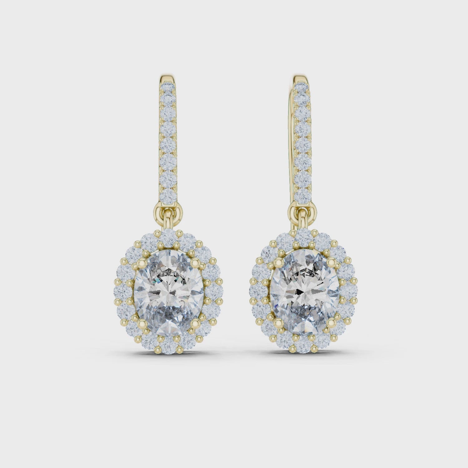 Oval Diamond Halo Drop Earrings. Crafted in radiant 18K Gold, a brilliant Oval-Cut Diamond is framed by a luminous pavé halo, maximising its size and fire