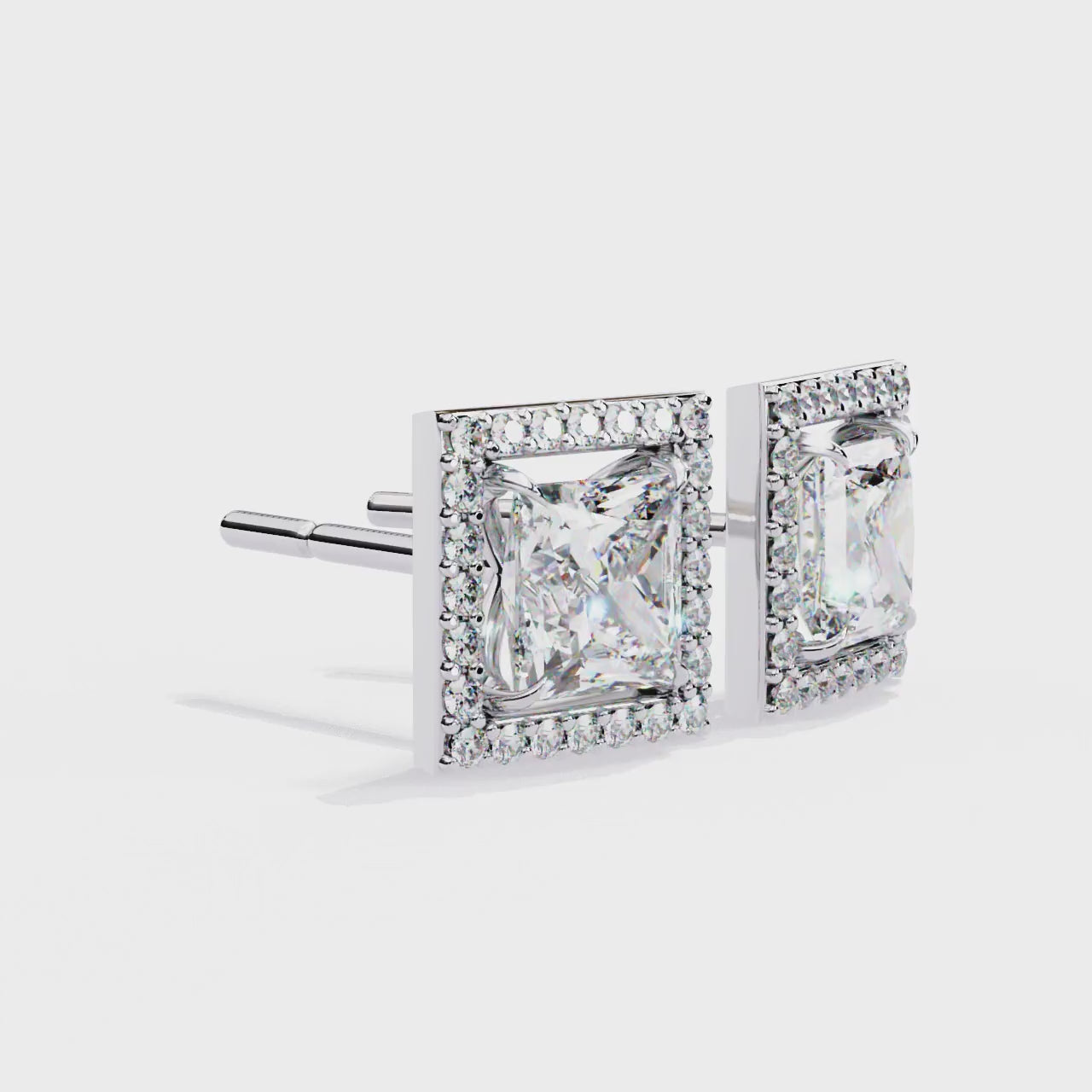 Pair of square-cut diamond earrings with gold frames on a white background