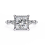 ring features a brilliant Princess-cut diamond framed by a delicate halo of round diamonds