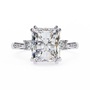ring features a commanding Radiant-cut solitaire flanked by two brilliant Round diamonds